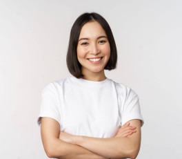 Portrait of happy asian woman smiling, posing confident, cross arms on chest, standing against studio background.